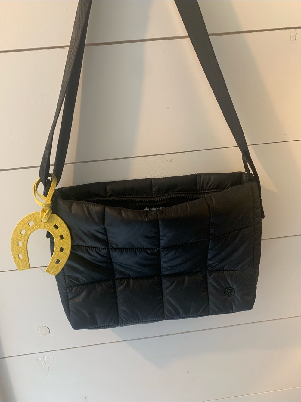 Lululemon black quilted cross body bag with adjustable strap and bag charm.
